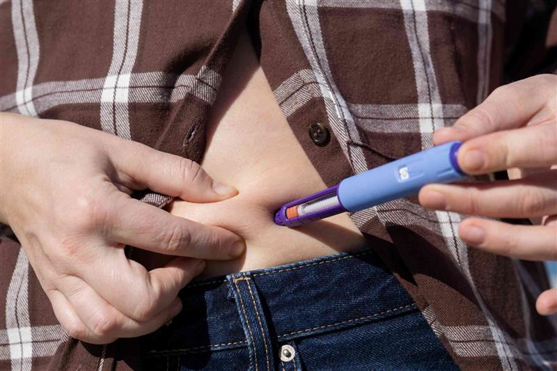Persona inyectándose un medicamento en la tripa.