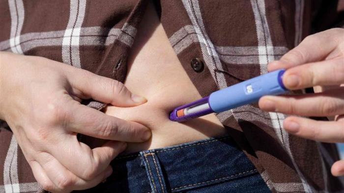Persona inyectándose un medicamento en la tripa.